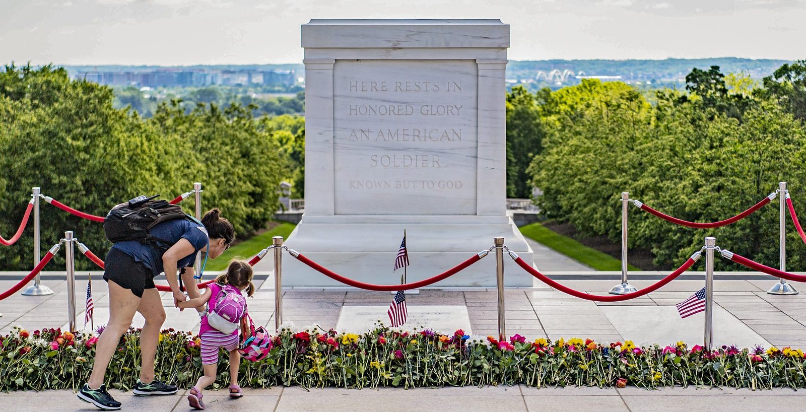 A mother and child placing a flower at the Tomb of the Unknown Soldier at Arlington National Cemetery